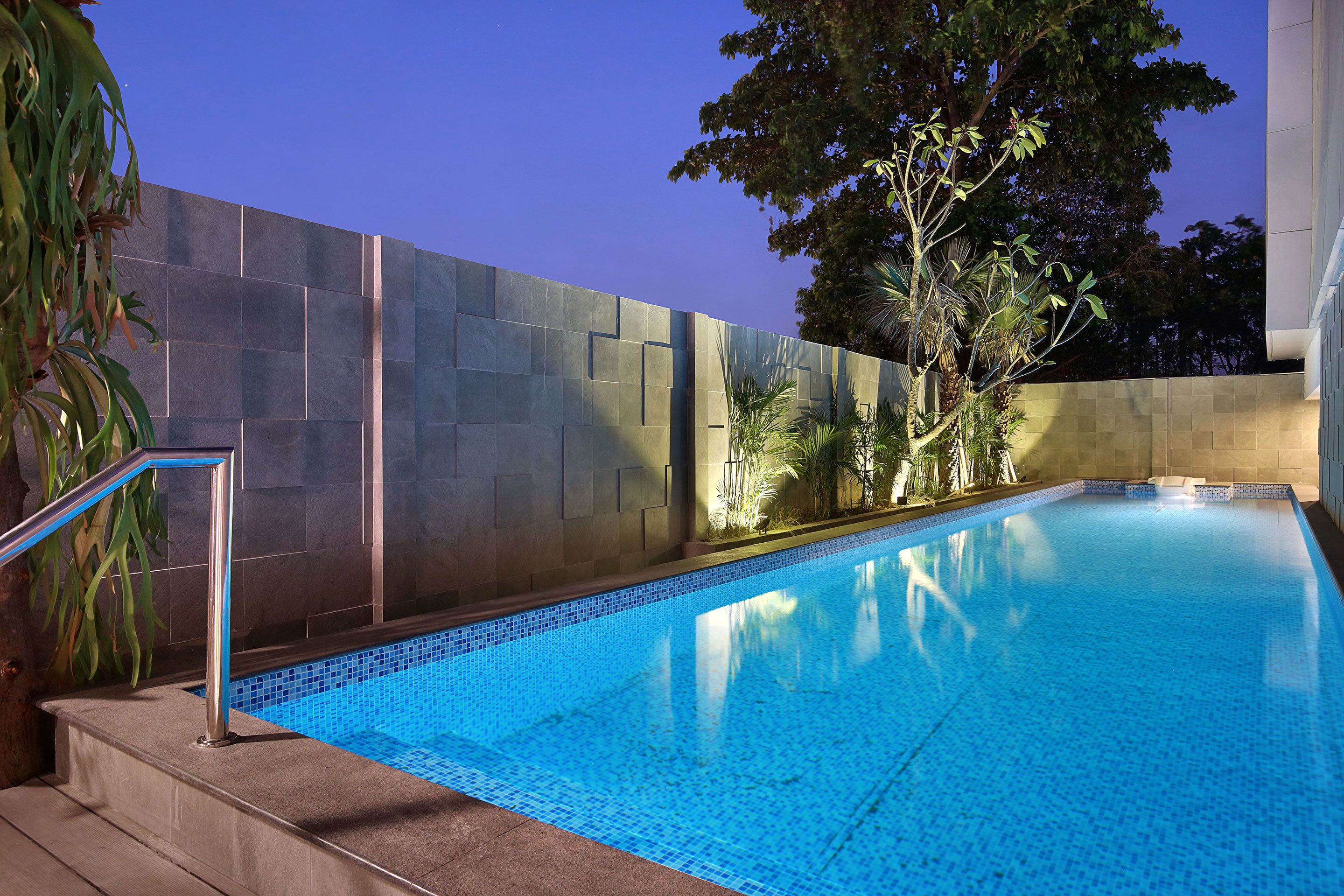 A swimming pool with a tiled edge, surrounded by a wall with a geometric pattern.