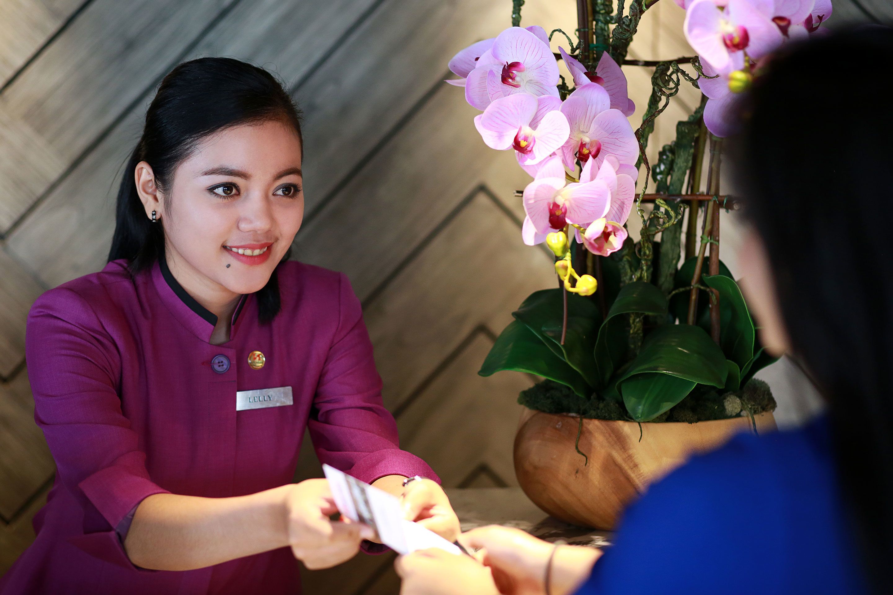 A person in a purple uniform with a name tag, handing over a card to another person.