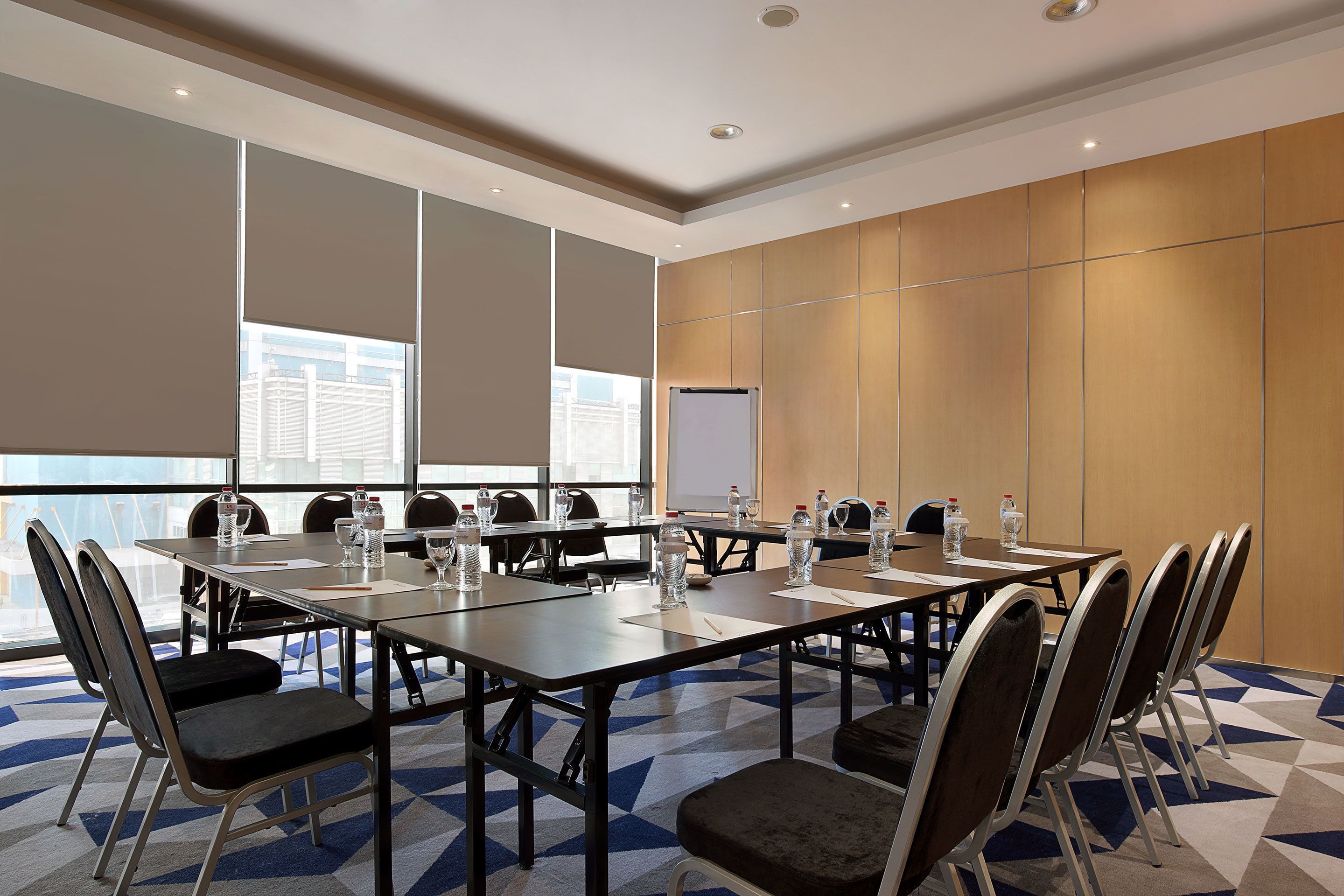 A conference room with a long table, chairs, water bottles, and a whiteboard.