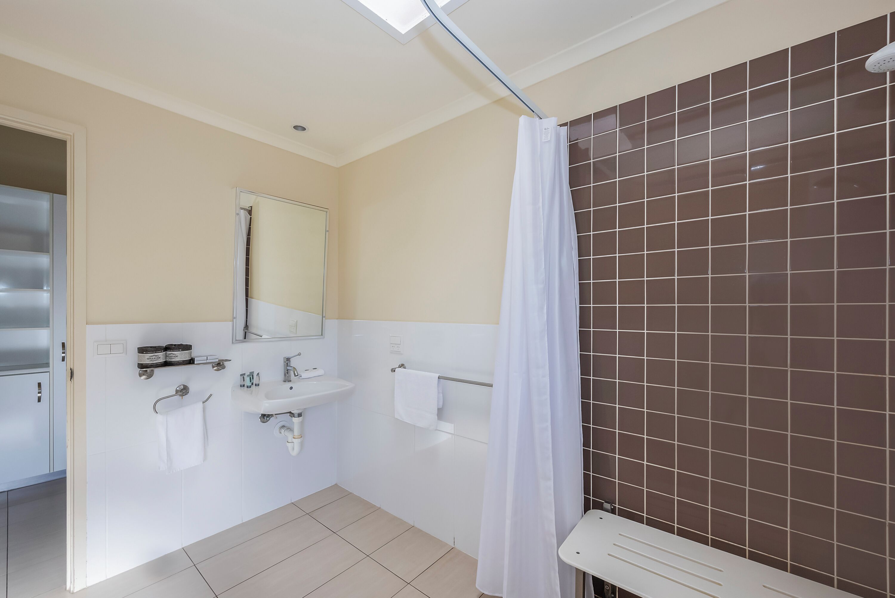 Een moderne badkamer met een wit wastafel, spiegel en handdoekhouder.