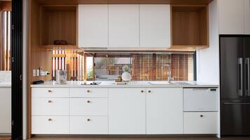 Una cucina moderna con mobili bianchi, elementi superiori in legno e un frigorifero in acciaio inossidabile.