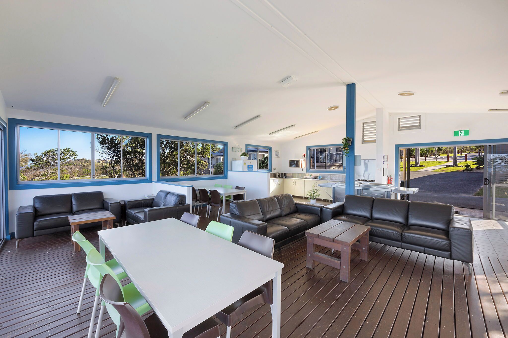 A modern lounge area with leather sofas, a dining table, and large windows offering views of the outdoors.