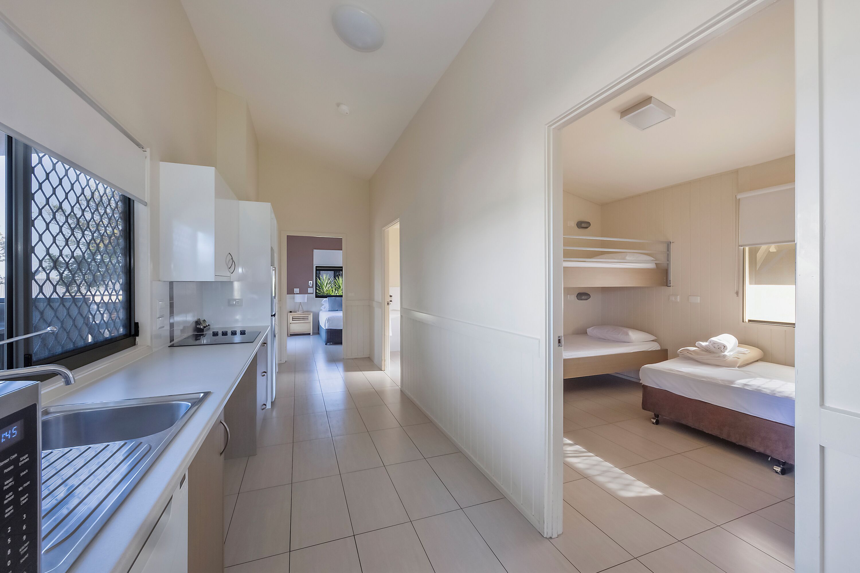 Una habitación de hotel moderna con kitchenette, baño y una habitación con literas.