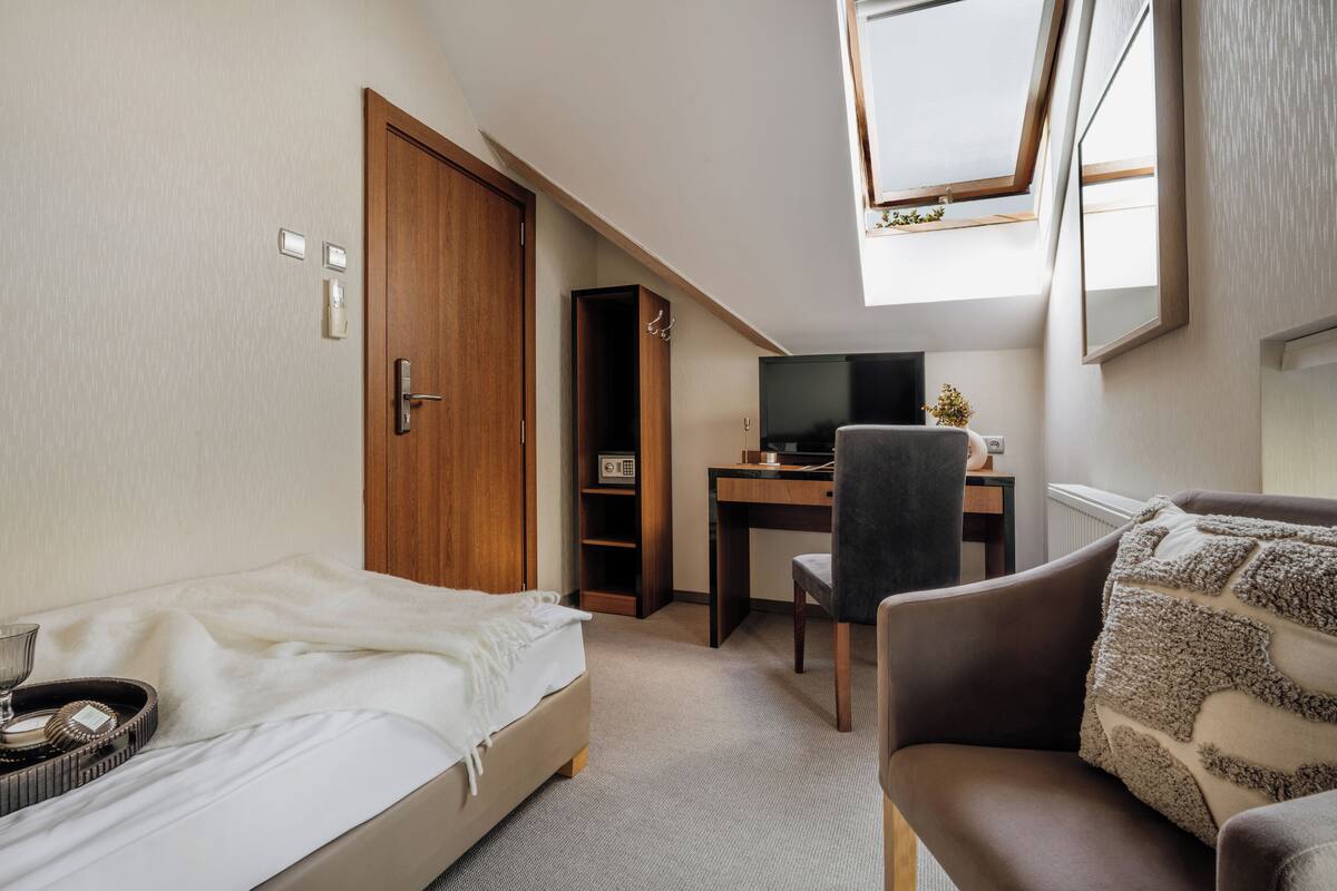 A bedroom with a bed, a desk, a chair, a TV, and a wardrobe.