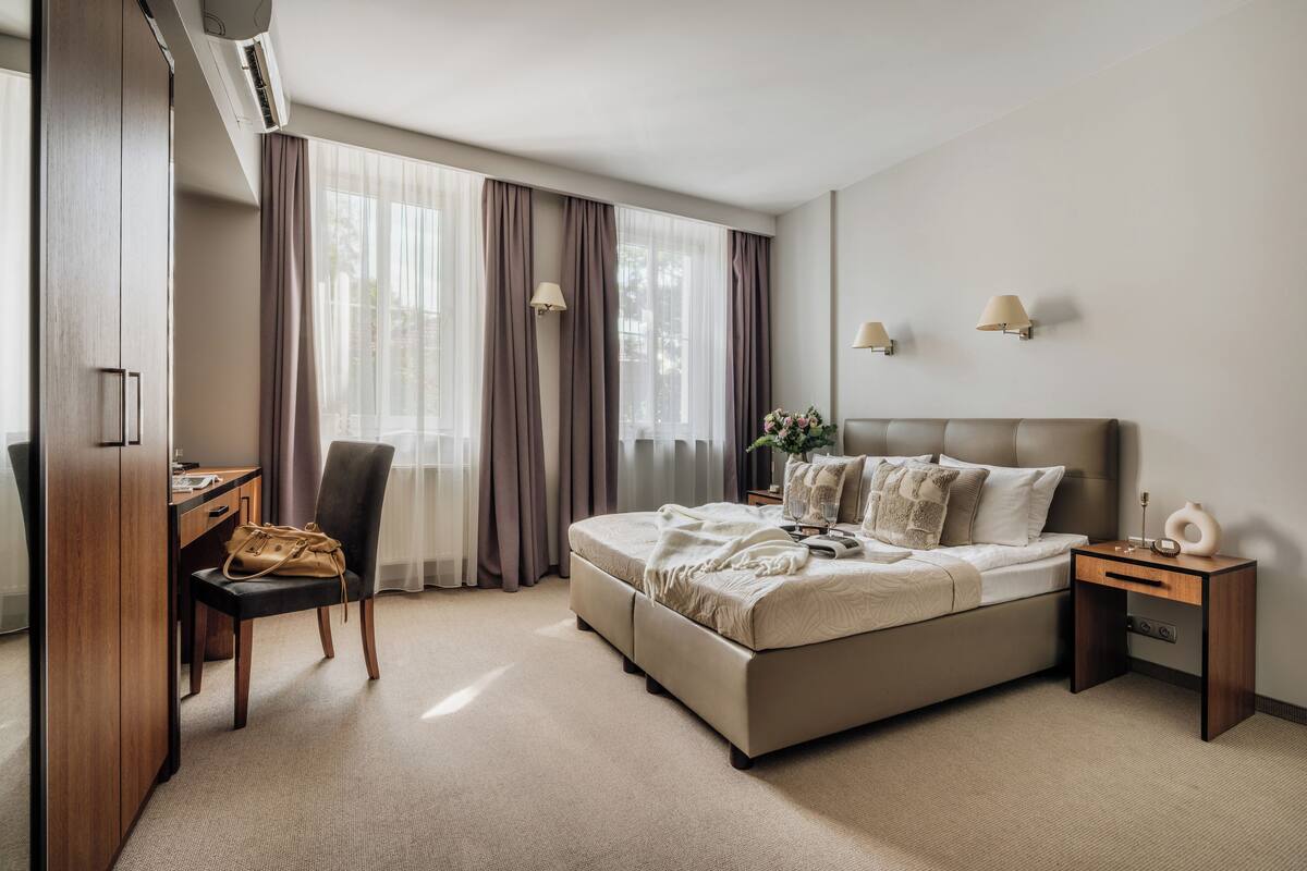 A bedroom with a bed, a desk, a chair, and a nightstand.