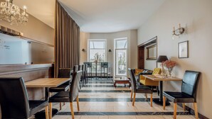 Un espace de restauration moderne avec un sol en marbre, des tables en bois et des chaises en cuir noir.
