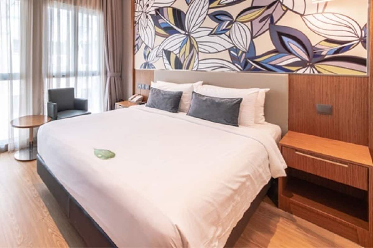 A hotel room with a large bed, a desk, a chair, and a small table.