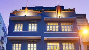 Un hotel de varios pisos con fachada moderna, ventanas iluminadas y una entrada destacada.