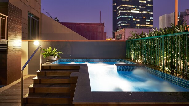 Una piscina en la azotea con vistas a un paisaje urbano al anochecer.