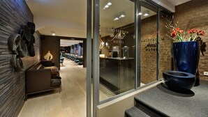 Un moderno vestíbulo de hotel con una pared de madera, una zona de estar y un ventanal con vistas al interior.