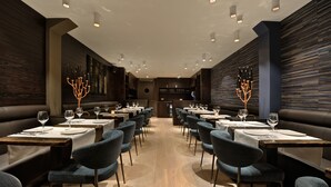 Un restaurante moderno con paneles de madera oscura, mesas de madera y sillas tapizadas en azul.