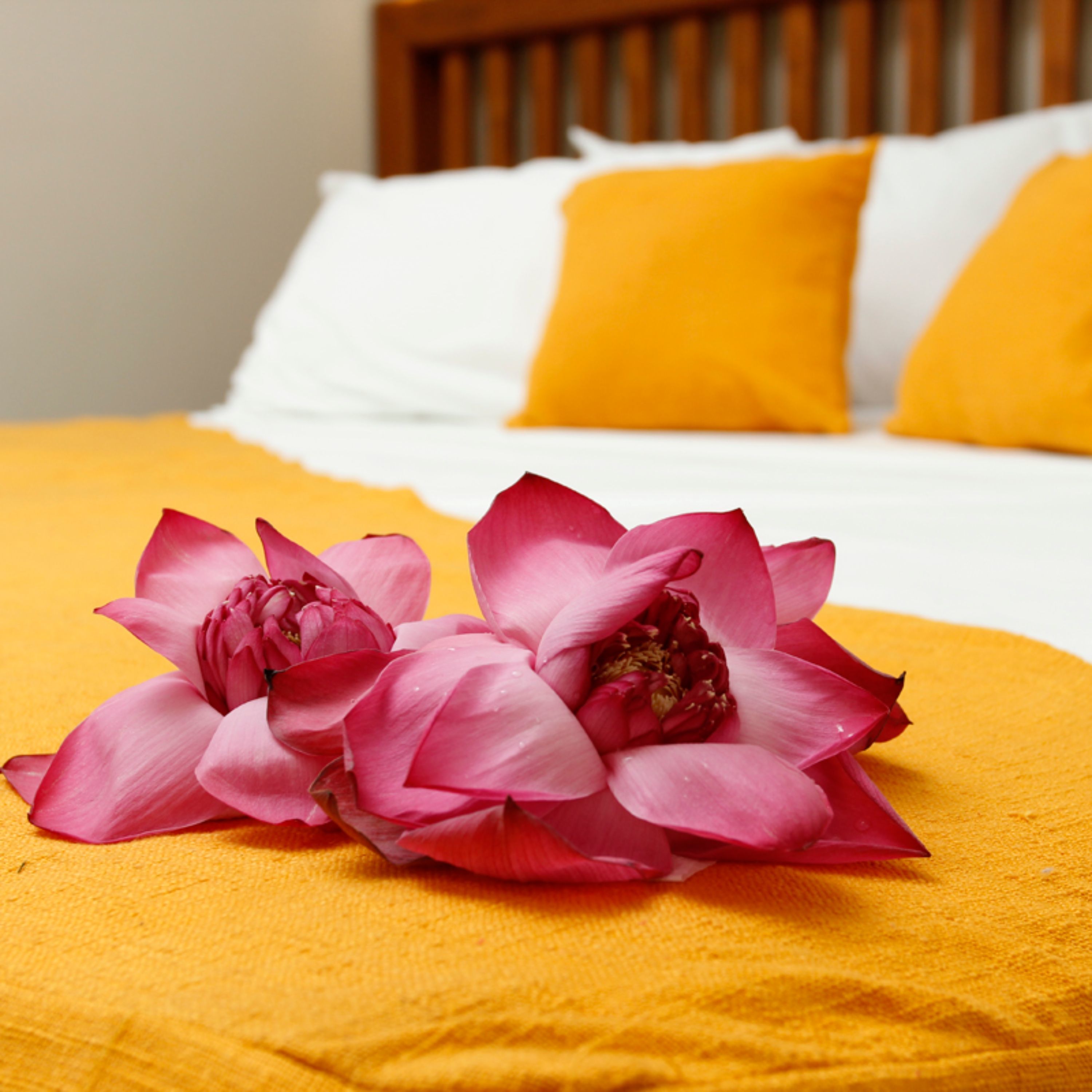 Una cama con una colcha amarilla y dos flores rosas encima.