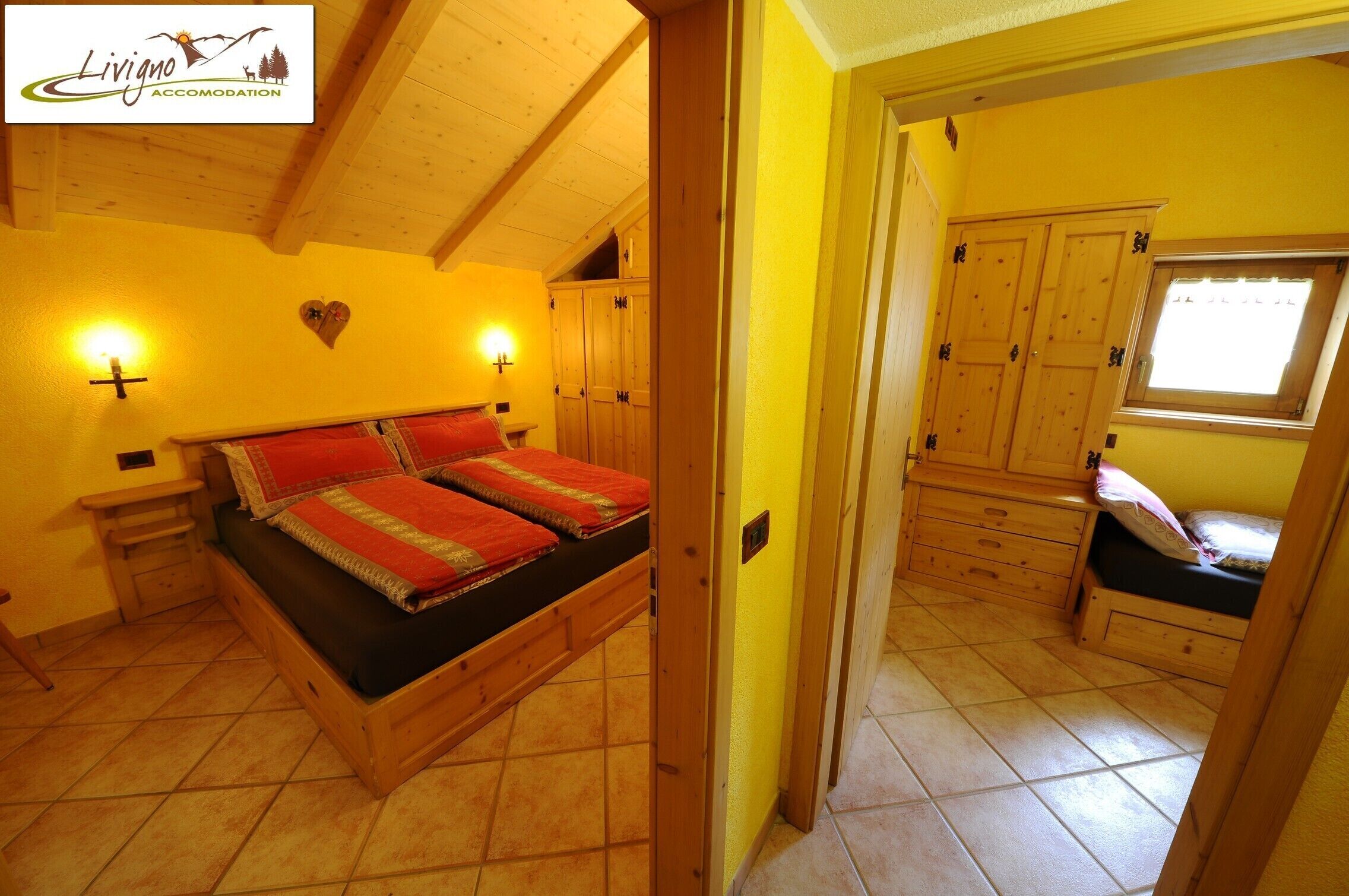 A bedroom with a wooden bed, two bedside tables, a nightstand, and a window with a view.