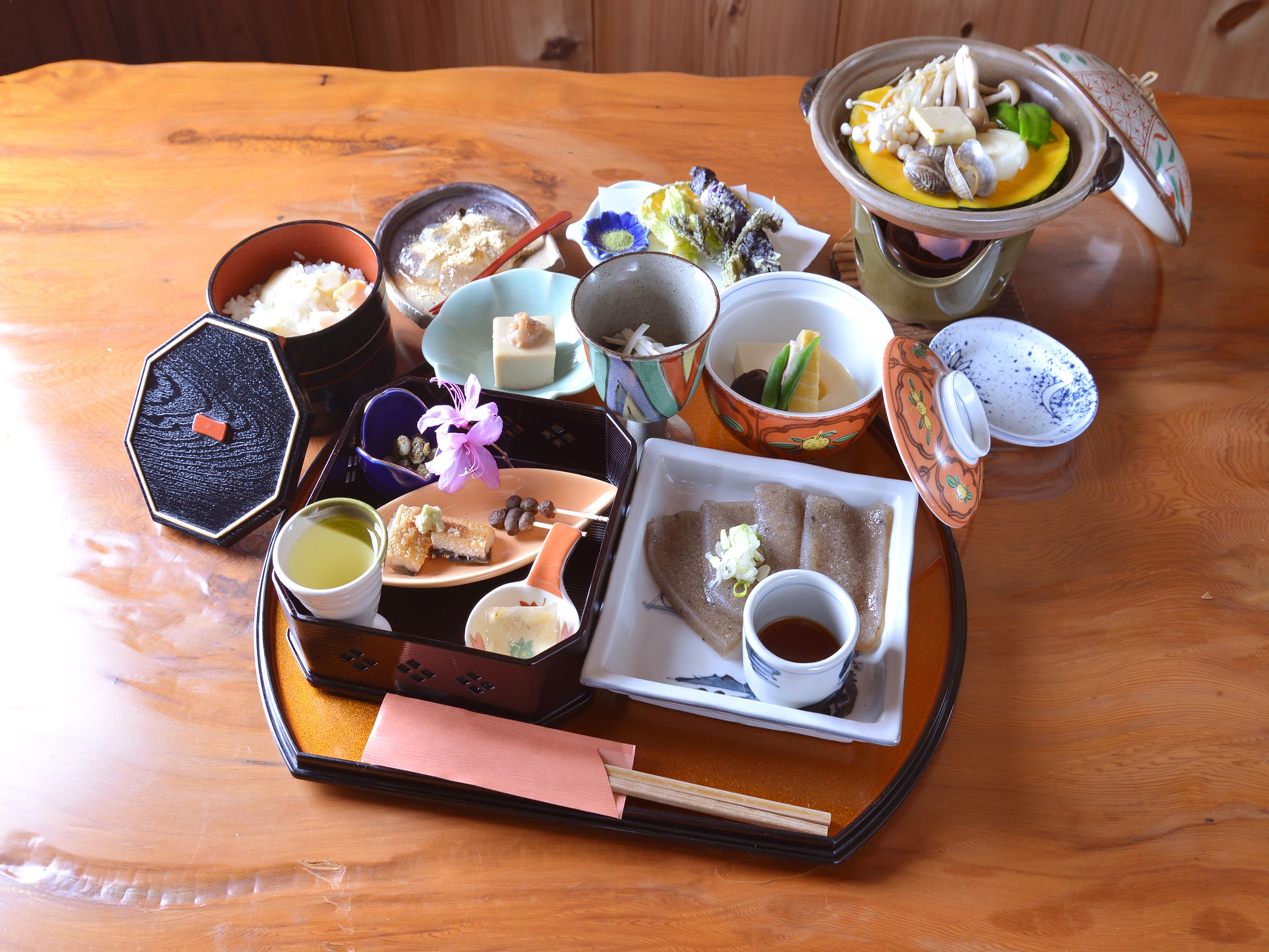 A traditional Japanese meal setup with various dishes and utensils on a wooden table.