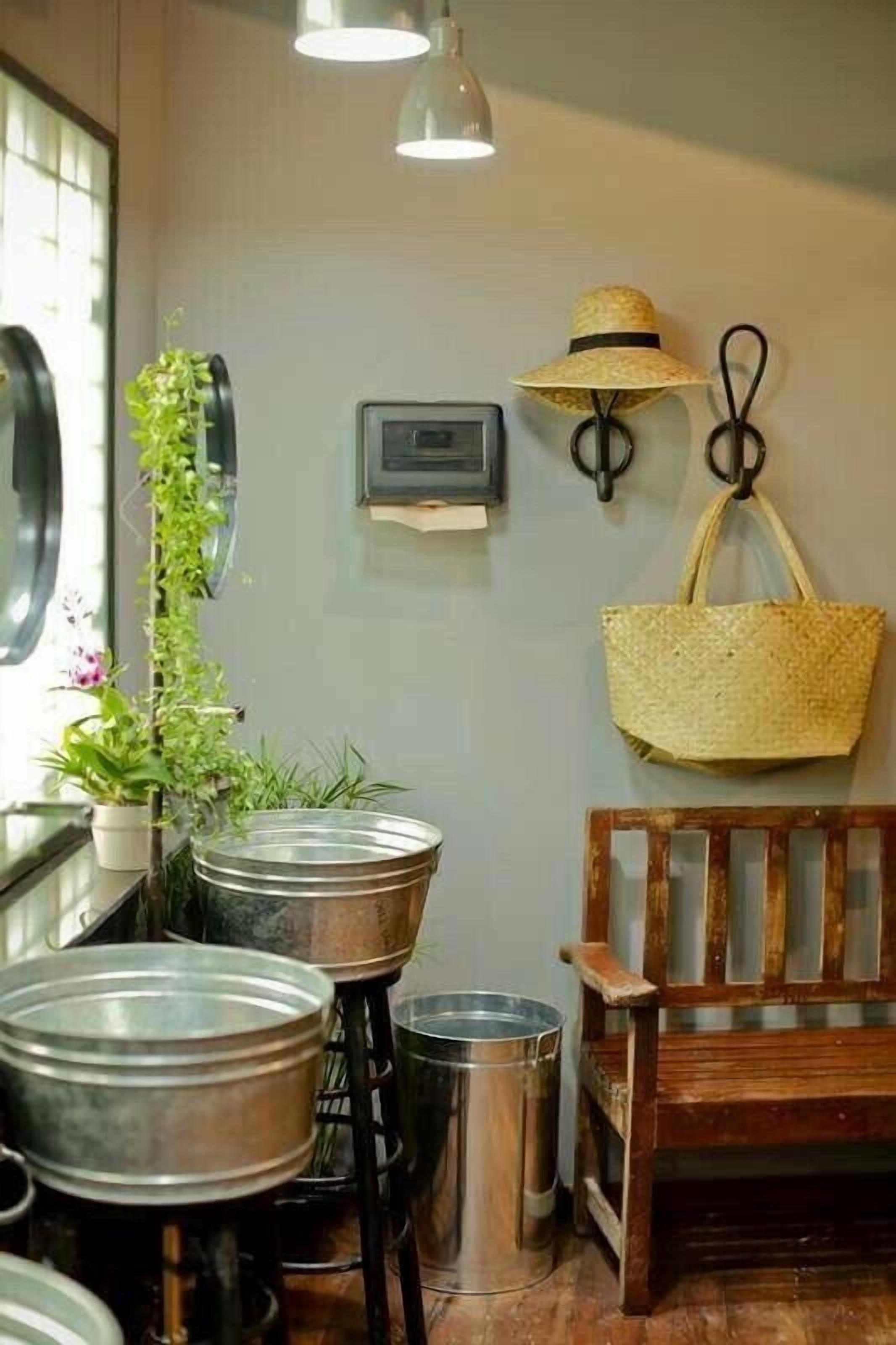 A kitchen area with a wooden bench, hanging baskets, and metal pots on stools.