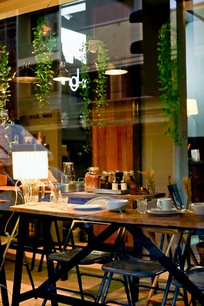 A restaurant with a wooden table set for two, hanging plants, and a visible menu board. - Bangkok Bed and Bike - Hostel (Bangkok)