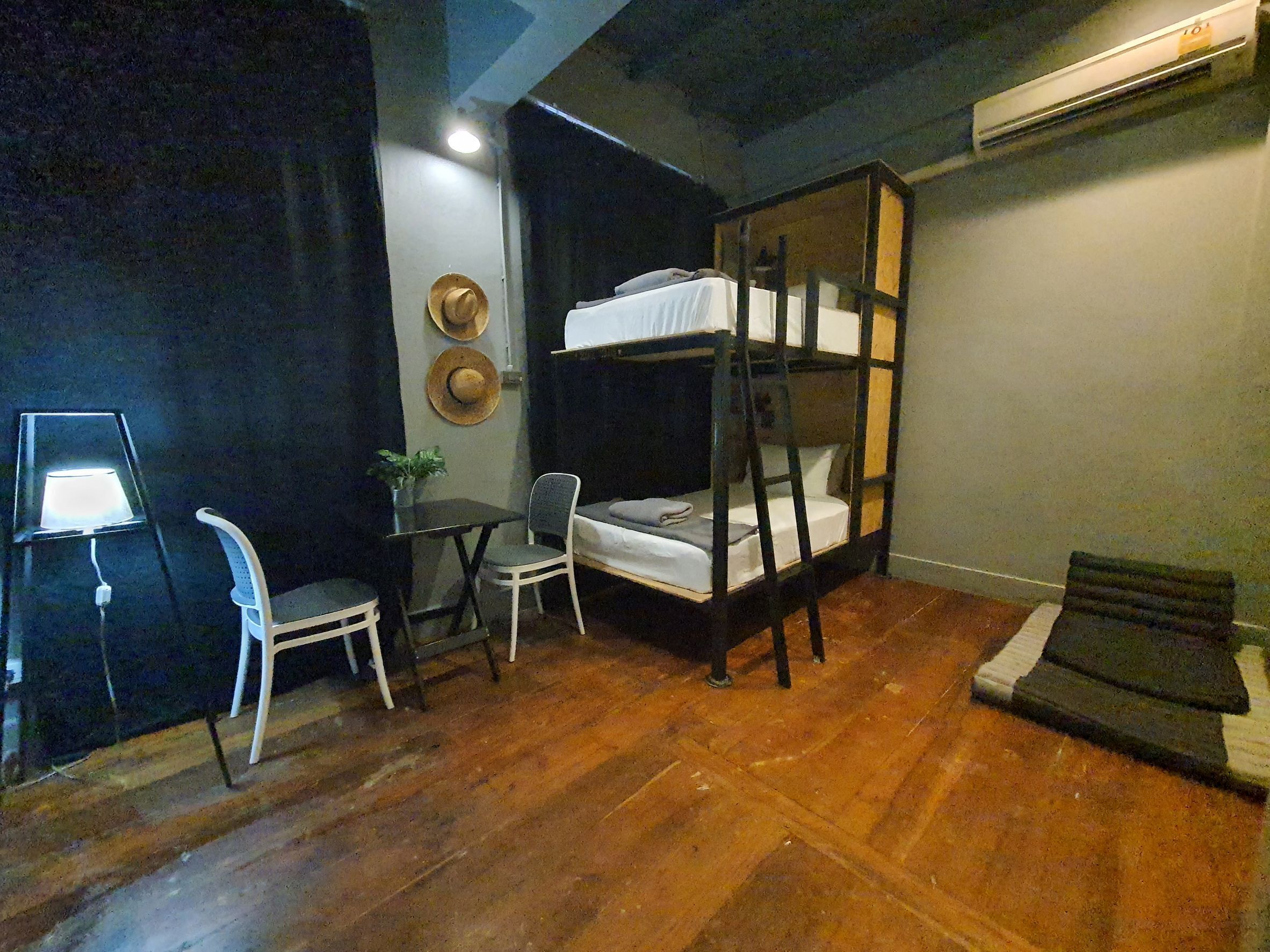 A room with a bunk bed, a desk with a chair, a small table, and a potted plant.