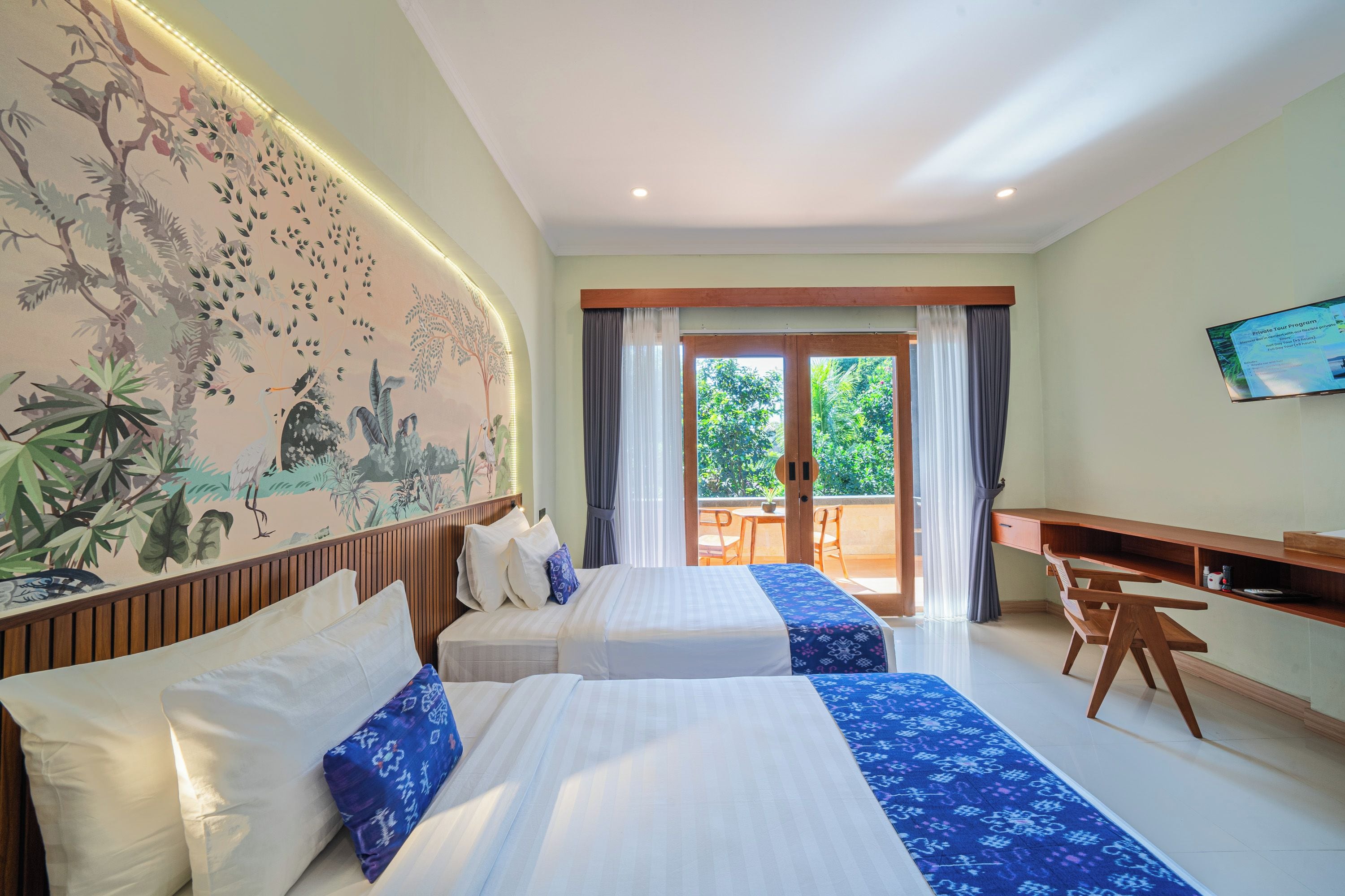 A hotel room with two beds, a desk, a chair, a television, and a view of the outdoors.