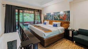 A bedroom with a large bed, a wooden headboard, a nightstand, a sofa, and a painting on the wall. - Dewangga Ubud (Ubud)