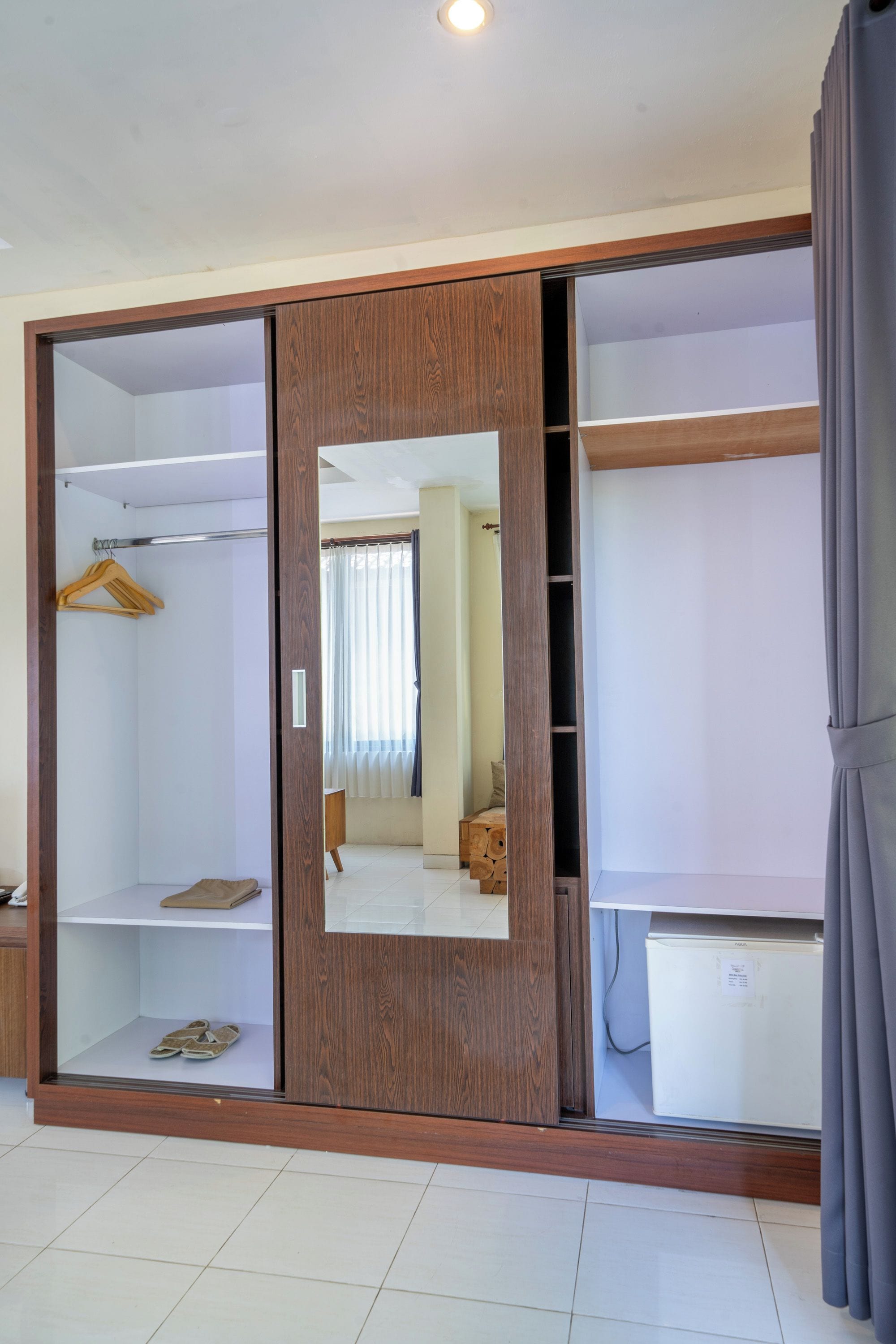 A room with a large wardrobe featuring multiple shelves and a mirrored door.
