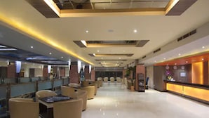 A spacious lobby with a reception desk, seating area, and a modern ceiling design.