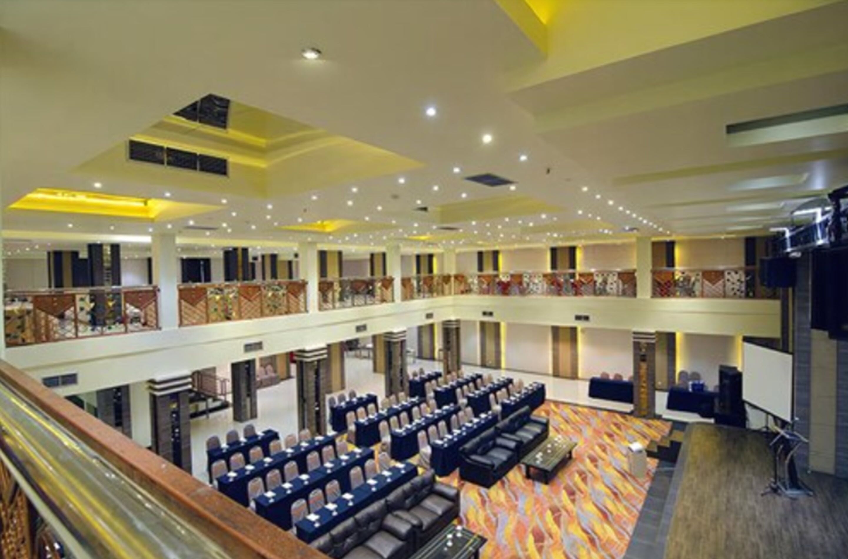 A multi-level hotel lobby with seating areas, a staircase, and a balcony.