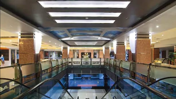 A spacious atrium with a central pool, glass railings, and a modern ceiling design.