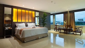 A modern hotel room with a large bed, a seating area with a view, and a large window.