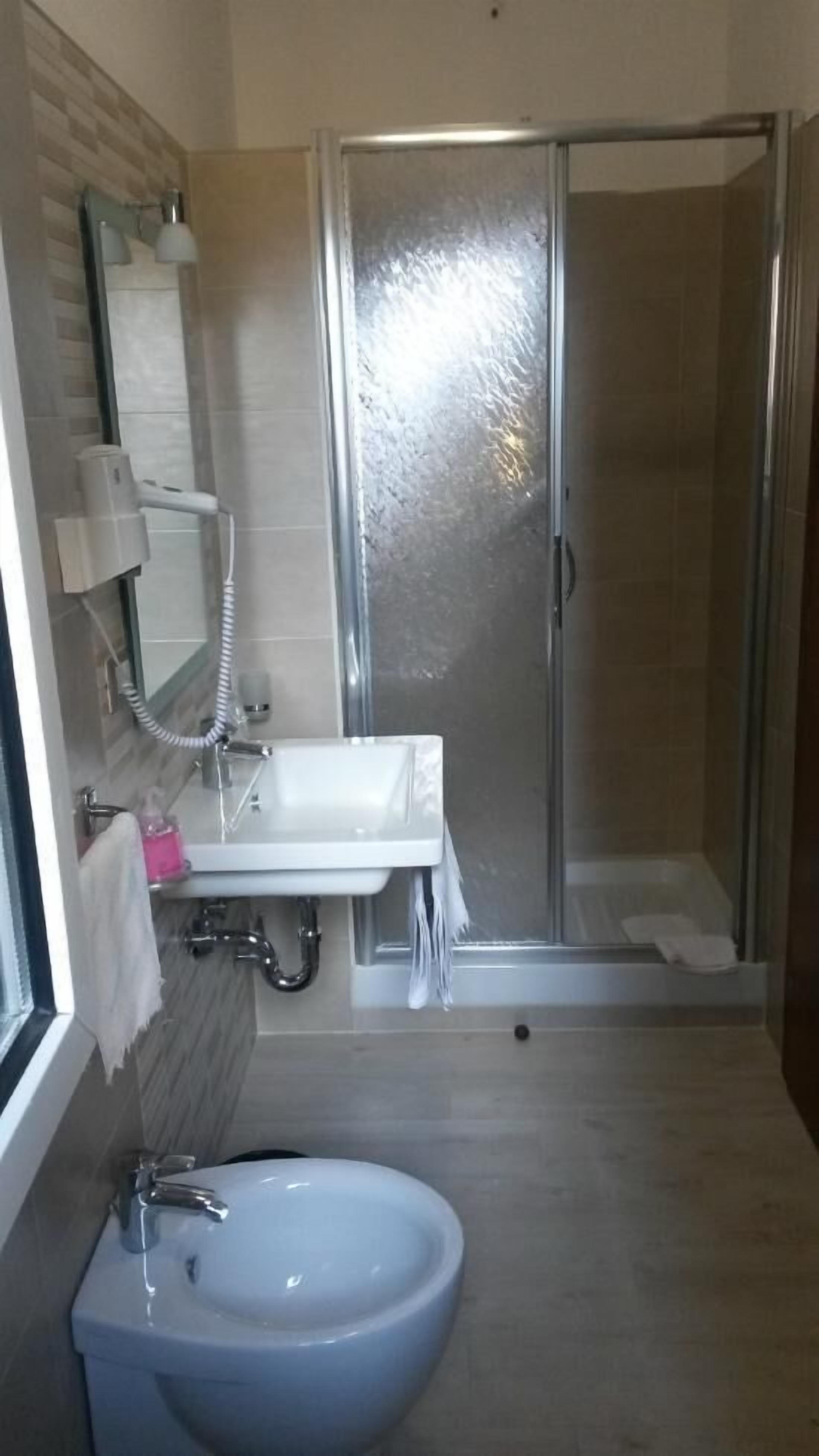 Un bagno con doccia, lavandino e specchio.