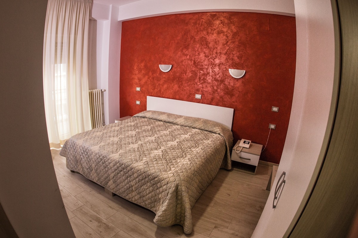 A bedroom with a bed, a nightstand, a telephone, and a wall-mounted light fixture.