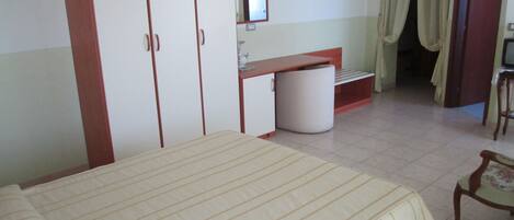 A bedroom with a bed, a wardrobe, a desk, a chair, and a bathroom visible through an open door.
