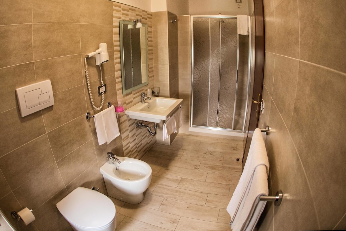 A bathroom with a toilet, bidet, sink, and glass shower enclosure.