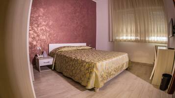 A bedroom with a bed, a nightstand, a dresser, and a window with curtains.