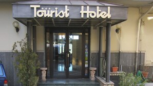 The entrance to a hotel with a sign reading "Tourist Hotel". There are steps leading up to the entrance, and two potted plants on either side. - Tourist Hotel (Potenza)