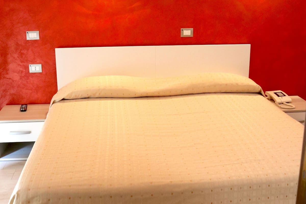 A bed with a white headboard, a beige bedspread, and two wall-mounted lights.