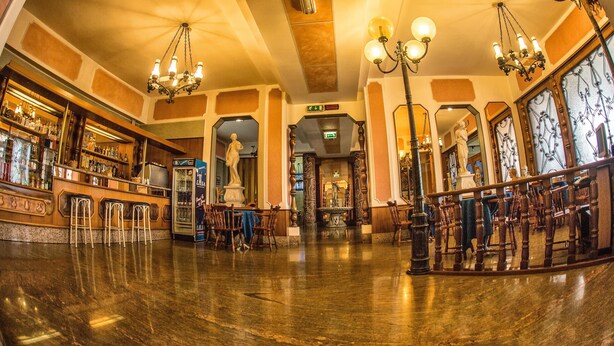 A bar area with a liquor display, seating, and a statue in the center. - Tourist Hotel (Potenza)