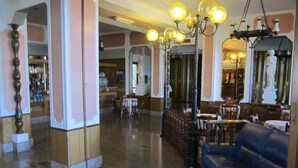 A lobby with a blue sofa, wooden columns, and a chandelier. - Tourist Hotel (Potenza)