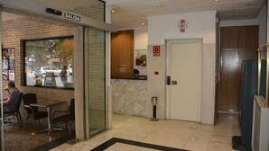 A hotel lobby with a reception desk, a sign reading "SALIDA," and a door marked with a red emergency exit sign. - Hotel Casa Emilio (Murcia)