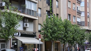 A hotel with a signboard, a balcony with potted plants, and a storefront with a white awning. - Hotel Casa Emilio (Murcia)