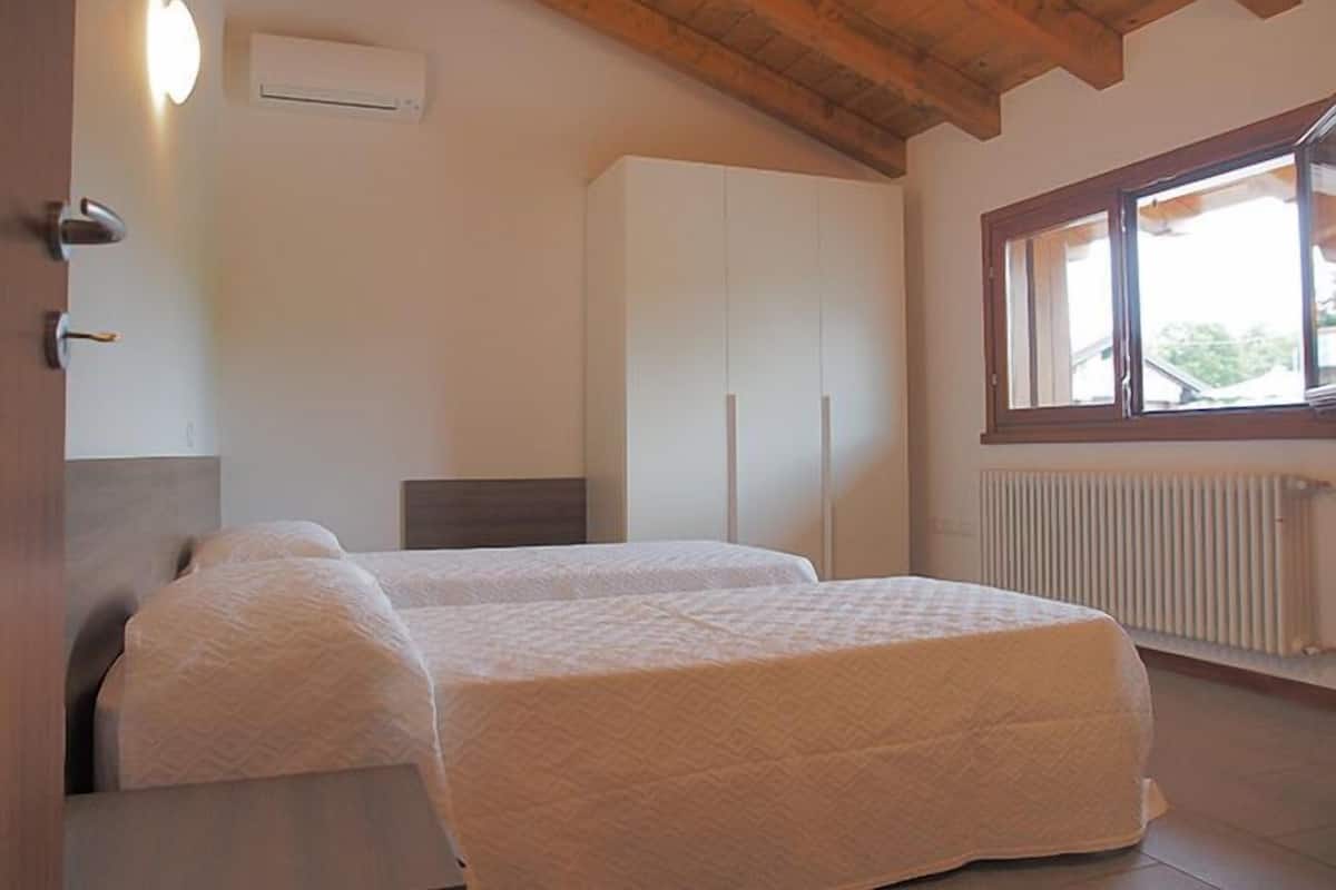 Quarto com duas camas, um guarda-roupa, um radiador e uma janela.