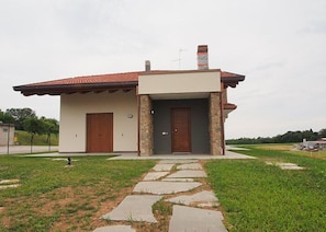 Una casa a un piano con tetto in tegole rosse, un camino in pietra e facciata in pietra.