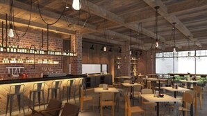 Een modern restaurant met bakstenen muren, houten tafels en stoelen, en hanglampen.