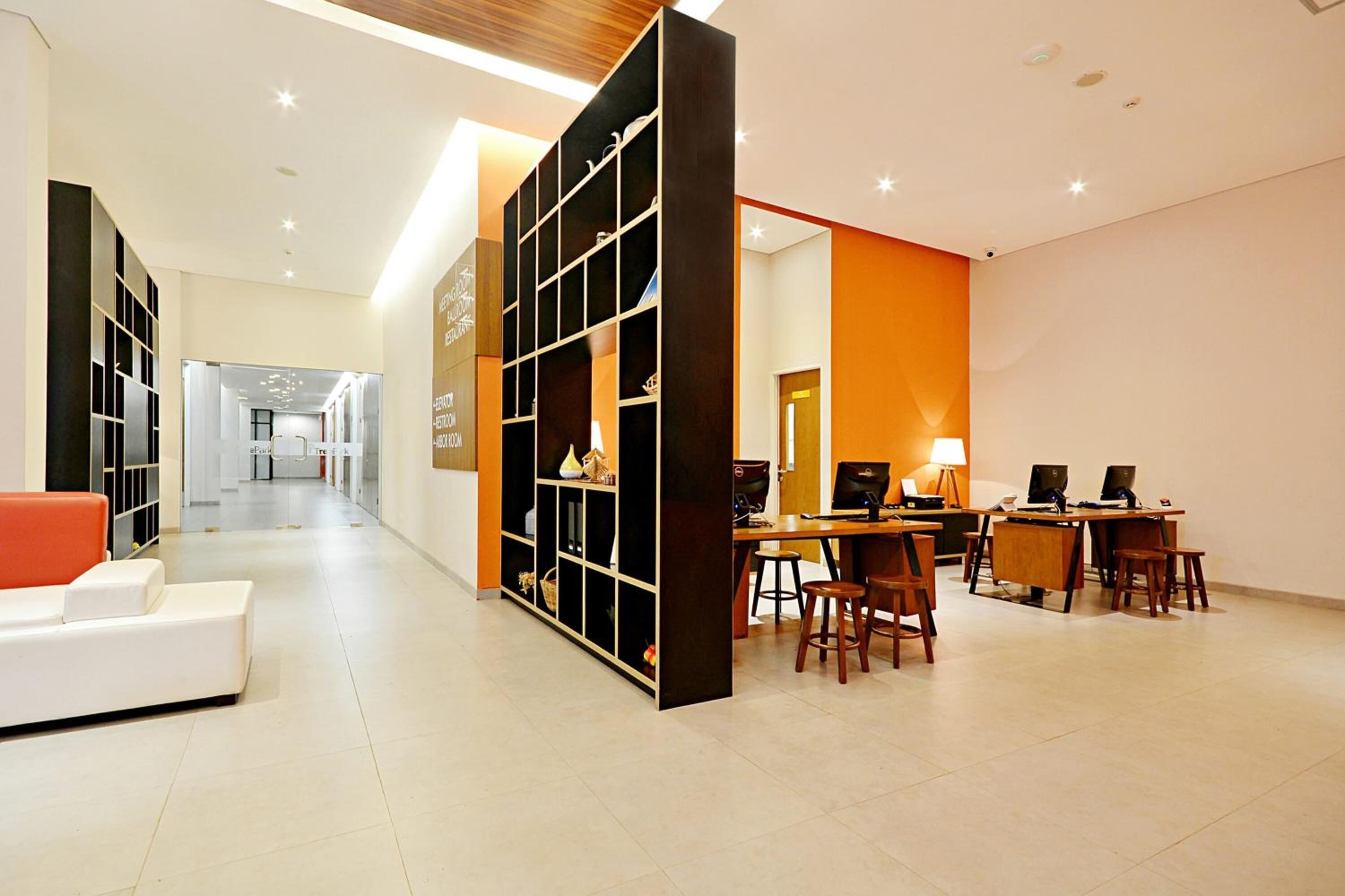 Um hall de hotel moderno com área de estar central, balcão de recepção e posto de informática.