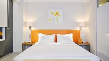 A hotel room with a large bed, two bedside tables, a nightstand, a wall-mounted lamp, and a framed picture on the wall.