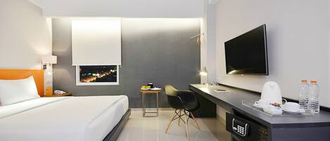 A modern hotel room with a bed, desk, chair, TV, and a night view on the wall.