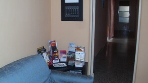 Un pasillo con un sofá azul estampado, un calendario enmarcado y folletos sobre una mesa.