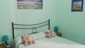 A bed with a metal headboard, two pillows with red patterns, and two bedside lamps.