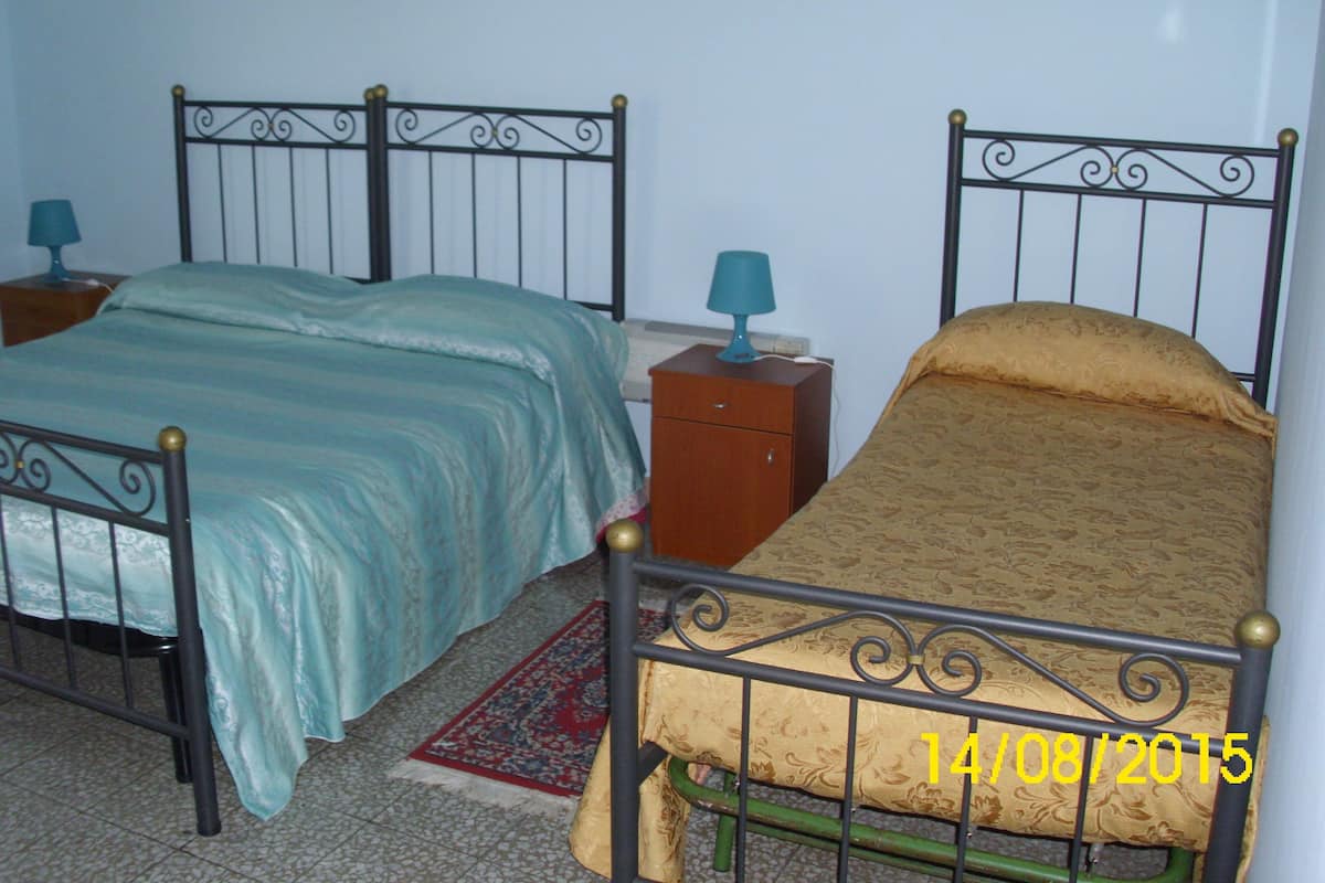 Une chambre avec deux lits, chacun doté d’une tête de lit d’un style différent et de tables de chevet avec des lampes.