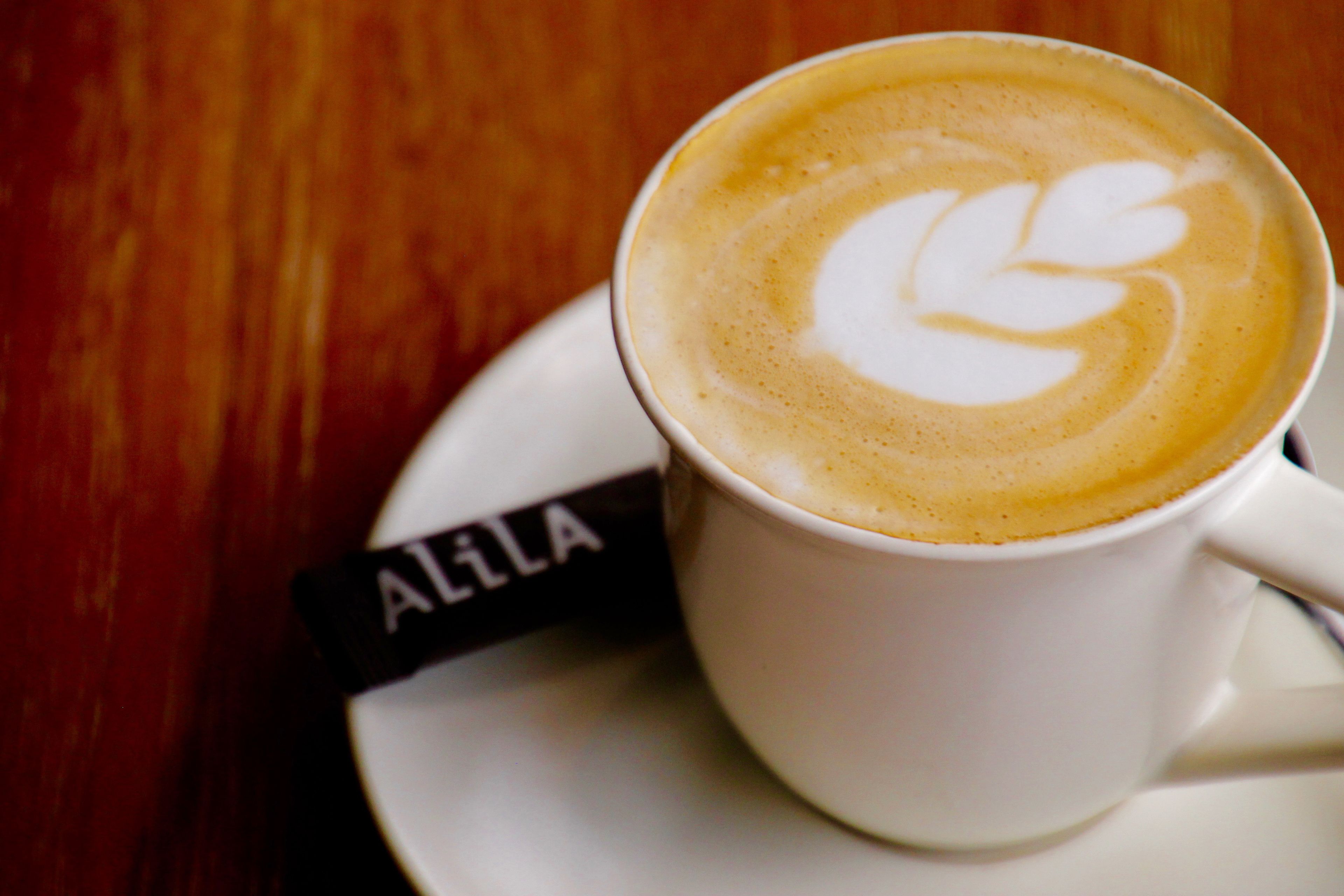 A cup of coffee with latte art on a saucer.