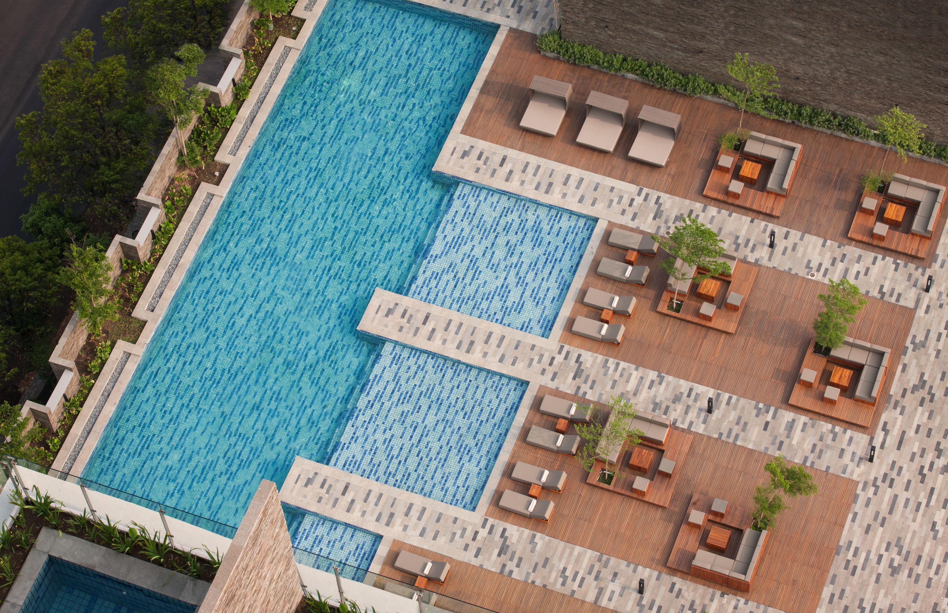 A large rectangular swimming pool with multiple lounge areas and planters.